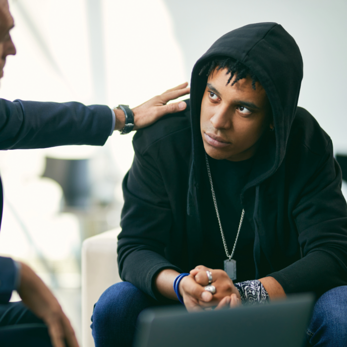 Young adult in hoodie talking with therapist